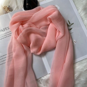 Close-up of pink silk scarf with soft chiffon texture draped on white faux fur background