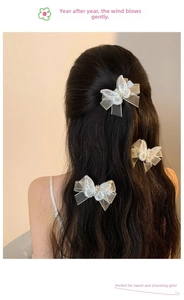 Three white mesh butterfly hair clips with pearls shown on long wavy hair back view