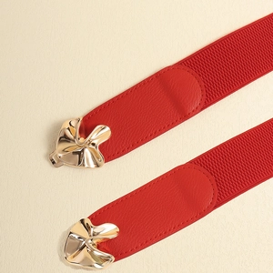 Close-up of red elastic belt with gold clover metal buckle and PU leather details