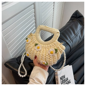 Detail of handmade knit bag with daisy flowers and elegant pearl shoulder strap