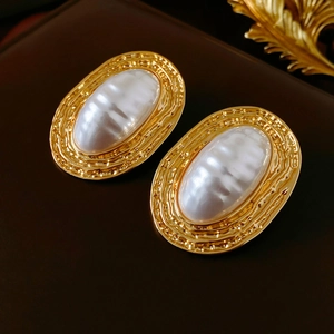 Macro shot of oval vintage gold metal earrings with white imitation pearls on leather