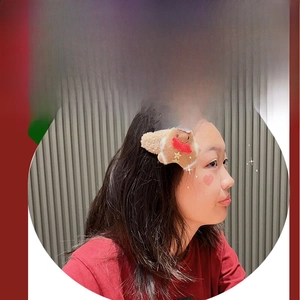 Close-up of plush gingerbread man hair clip with a tiny red hat and festive scarf