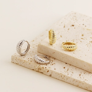Detail view of gold and silver S925 sterling silver croissant hoop earrings on stone