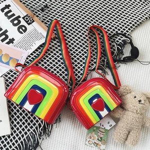 Detailed view of rainbow crossbody bags with heart patches and wide striped straps