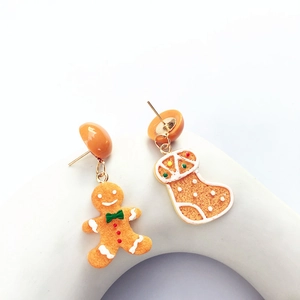 Close-up of asymmetric Christmas stud earrings featuring gingerbread man and stocking