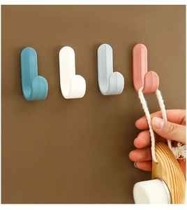 Detail showing hand hanging a wooden brush on a dark blue J-shaped wall hook in a home setting