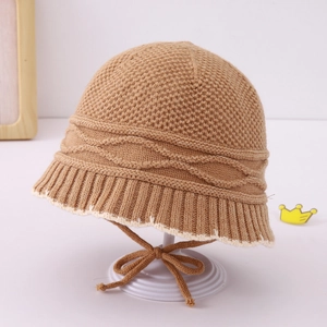 Macro detail of brown knitted baby bucket hat with pineapple texture and white stitching