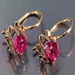 Detalle de los pendientes dorados vintage con piedras rosas ovaladas y engaste de garras