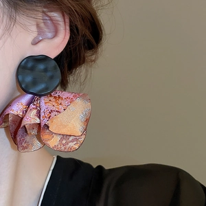 Detail of vintage oversized drop earring with black hammered metal and gold brocade fabric