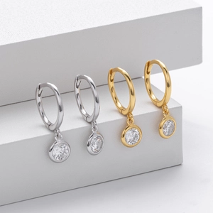 Macro detail of 925 silver hoop earrings with round sparkling gemstones on white steps