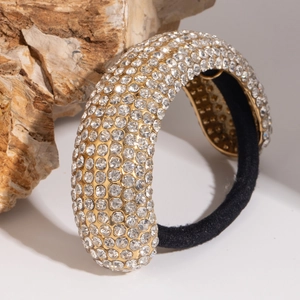 Macro shot of sparkling rhinestone-encrusted gold-finish hair ring with thick elastic