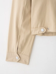 Dettaglio giacca in twill beige con bottoni metallici su polsini e orlo
