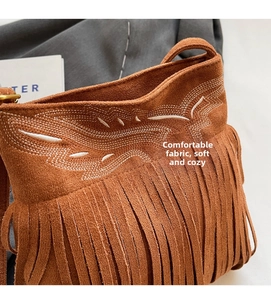 Detail of brown suede tassel bag with fine white embroidery and bohemian style fringe