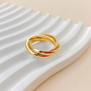 Macro shot of interlocking triple-ring gold band on a white ceramic display tray