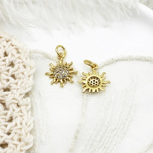 Detailed view of two golden sunflower charms with small crystals on white lace background
