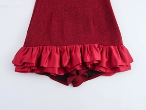 Dettaglio dell'abito in tweed rosso con orlo a balze in raso e vita alta su bianco