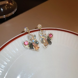Detailed macro view of heart-shaped earrings with multi-color crystals on a white plate
