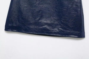 Détail macro de l'ourlet de la jupe en cuir bleu foncé avec texture brillante et couture