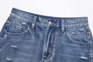 Close-up of waistline detail on distressed denim shorts with metal button and ripped edges