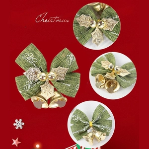 Detail of green burlap Christmas bow with golden bells and white Merry Christmas print