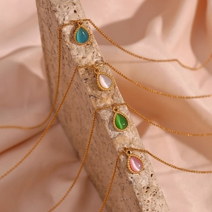 Close-up of teardrop cat-eye stone pendants in four colors on elegant gold chains