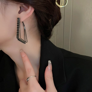 Dark aesthetic geometric silver needle earrings with black crystals worn by model