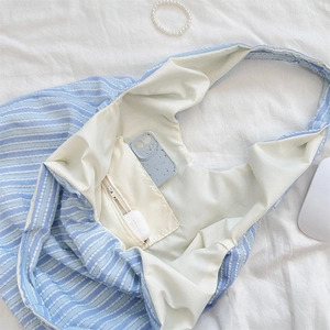 Blue striped canvas tote detail showing inner zipper pocket with phone and earphone storage