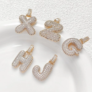 Macro shot of gold-plated alphabet pendants featuring micro-pave cubic zirconia crystals