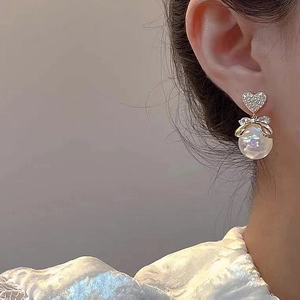 Detail von herzförmigen Perlenohrringen mit Strass und Schleife am Modell