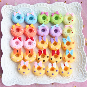 Flat lay of colorful resin donut charms with bows for DIY craft projects and decoration