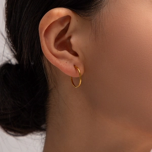 Gros plan de boucles d'oreilles cœur en acier inoxydable plaqué or 18 carats sur modèle