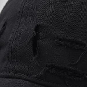 Macro shot of black distressed cotton baseball cap showing twill texture and ripped details
