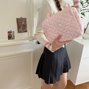 Détail de la trousse de maquillage rose matelassée avec motif de lapin et fleurs en main