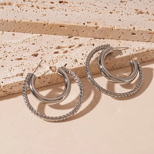 Detail of silver double-layered C-shape hoop earrings with smooth and textured metal finish