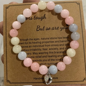 Macro view of 8mm pink zebra stone beads with a silver heart charm on kraft card