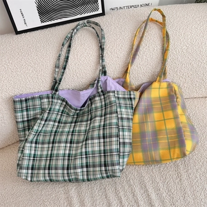 Close-up of checkered canvas tote bags in green and purple colors on a white sofa