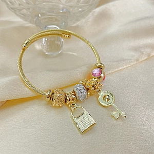 Detail of gold beaded bracelet with crystal beads and heart key charm on satin
