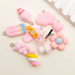 Flat lay of pink resin charms including ice cream, clouds, and bears for DIY crafts