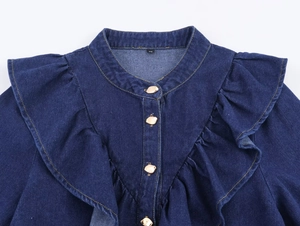 Détail de chemise en jean bleu foncé avec volants, col montant et boutons dorés