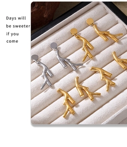 Detailed close-up of tree branch earrings in gold and silver finish on a velvet tray