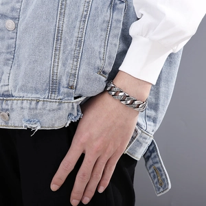 Close-up of men's silver Cuban link bracelet with Greek key pattern on a model