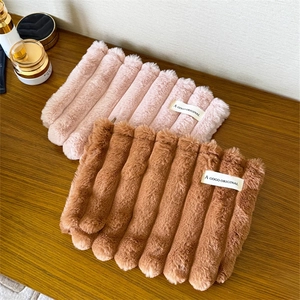 Detailed top view of pink and brown striped plush cosmetic bags on a wooden surface