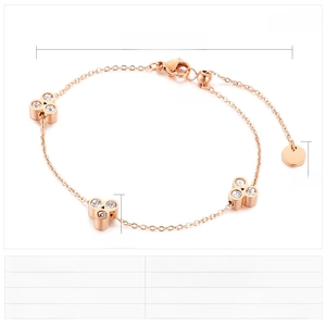 Detail of rose gold stainless steel bracelet with clover pendants and crystals