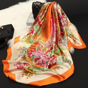 Detail of vibrant floral print silk square scarf with bright orange stitched edges