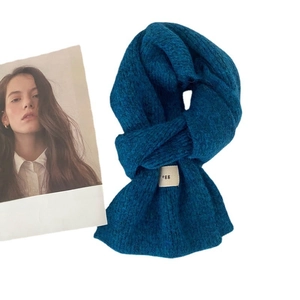 Soft wool-blend knitted blue scarf with minimalist egg brand label and warm texture
