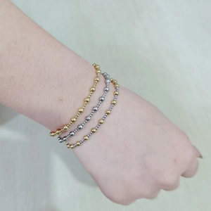 Detail of three-piece 18K gold and silver beaded stretch bracelets on a wrist