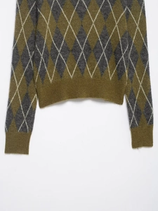 Detail of argyle knit polo shirt featuring ribbed cuffs and green grey texture