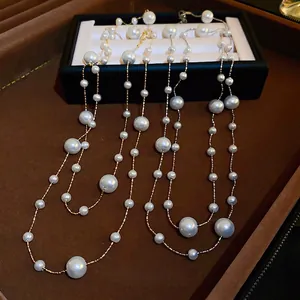Gold and silver layered pearl tassel necklaces on a luxury brown velvet jewelry display