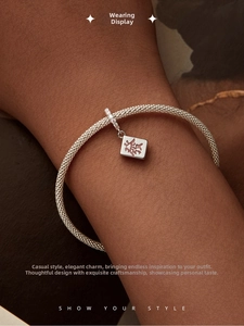 Macro detail of a 925 silver mesh bracelet featuring a red Mahjong charm on the wrist