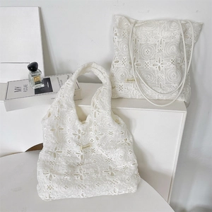 Détail de sacs fourre-tout en dentelle blanche brodée avec motifs floraux ajourés élégants